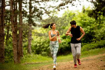 Fototapeta premium Young fitness couple running at the forest trail