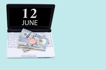 Laptop with the date of 12 june and cryptocurrency Bitcoin, dollars on a blue background. Buy or sell cryptocurrency. Stock market concept.