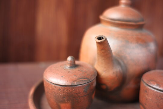 kettles and glasses handmade with clay materials. traditional Javanese kitchen tools used for warm drinks. Indonesian red kitchen utensil on a wooden background