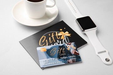Gift card and smartwatch on light background