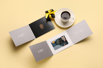 Gift card and cup of coffee on color background
