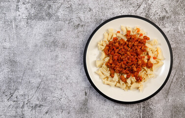 Fototapeta na wymiar Traditional pasta bolognese on a round plate on a dark grey background. Top view, flat lay