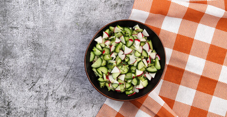 Cucumber and radish salad in a bowl  on a dark grey background. Top view, flat lay