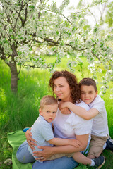 picnic. mother with sons cuddle in flowering garden. mother's day