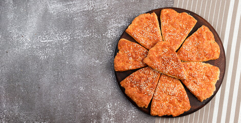 Cheese scones on a round wooden cutting board on a dark background. Top view, flat lay