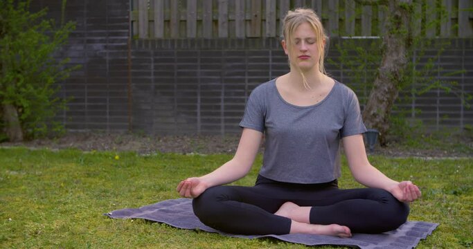 A Young Woman Doing Yoga In The Backyard