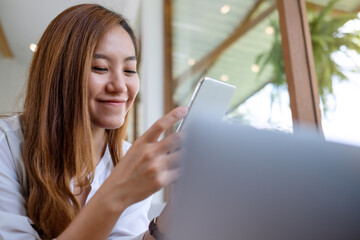Fototapeta premium A beautiful young asian woman holding and using mobile phone