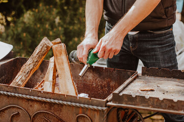 Man's hands setting fire at barbecue by gas burner on the back yard.