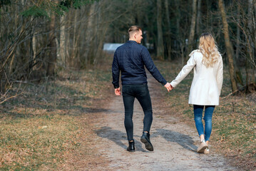 Obraz premium Beautiful loving couple going for a walk in a forest in the spring,autumn outdoors sunny day.Rear view.