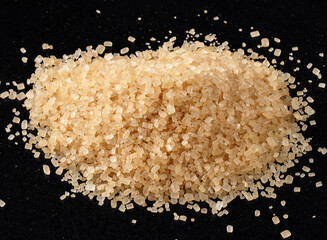 pile of demerara brown sugar closeup on black