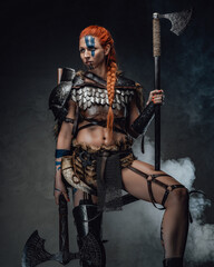 Scandinavian woman barbarian with painted face and two axes in fog
