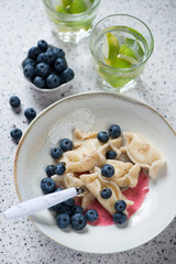 Beige plate with cottage cheese dumplings and bilberries, elevated view, vertical shot