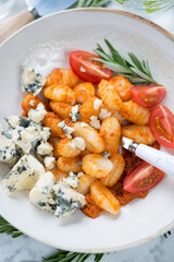 Close-up of potato gnocchi with sun dried tomato pesto, cherry tomatoes and gorgonzola cheese, vertical shot, above view
