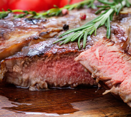 sliced beef steak with herbs and tomatoes on wooden desk