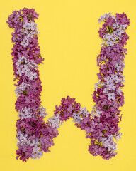 The letter W is lined with lilac flowers on a yellow background. For lettering, composing words.