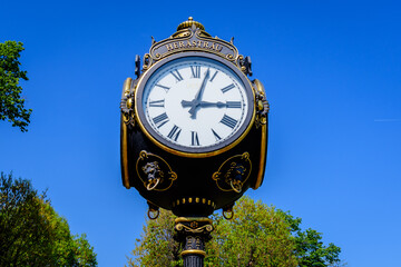 Fototapeta na wymiar Vintage style black and grey metallic clock towards clear blue sky in King Michael I Park (former Herastrau) in Bucharest, Romania, in a sunny spring day.