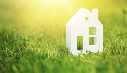 Sculpture of a house made of white clay on green grass in the sunlight