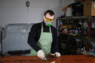 Photo of a caucasian male painter with a brush paints in a mask in a workshop