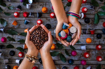 Coffee beans roasted, instant and grinded coffee in the mugs and coffee capsules in the hands of two woman