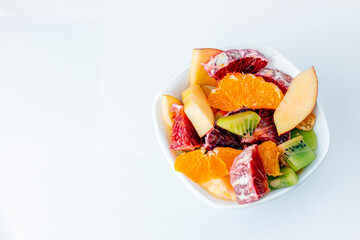 Fruit salad in ceramic bowl isolated on white background Delicious cut fruits close up background. Grapefruit, orange, kiwi and apple.