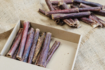 Half-empty Cardboard Pet Treat Box on burlap fabric. Dried dog g