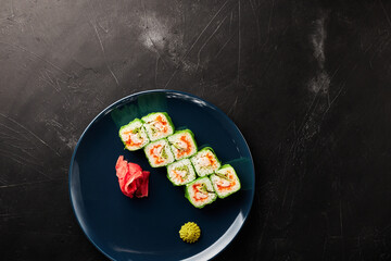 rolls in green rice paper in a blue plate on a black textured background