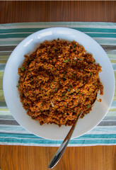 an aperitif from traditional Turkish cuisine; Kısır made with crushed wheat, tomato paste and finely chopped greens. Top view.