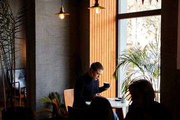 Young girl with short hair and nose piercing sits in a cafe and work at a tablet. The concept of...