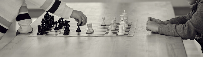 2 boys play chess with each other child hand making right move banner