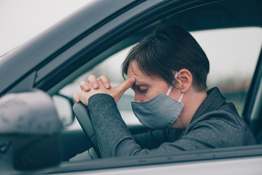 Disappointed female driver with protective face mask sitting in the car during Covid-19 pandemics