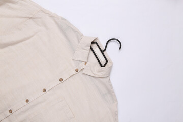 Beige cotton shirt on a hanger lies on a white background