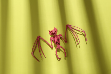 Pink bat skeleton on a green background with trendy striped shadow. Minimalism. Abstraction. Concept art