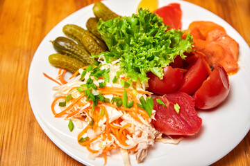 Pickled sauerkraut, cucumbers and tomatoes on a white plate. Close-up, selective focus