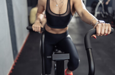 Fototapeta na wymiar Woman doing intense cardio training on exercise bike. Fitness female using air bike for cardio workout at gym