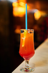 Red alcoholic cocktail with ice and straw. Close-up, selective focus