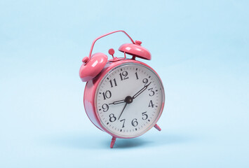 Levitating pink alarm clock on colored background. 3D photo. Minimalistic still life. Creative layout. Concept art