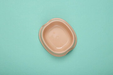 Empty bowl for cat food on blue background. Top view