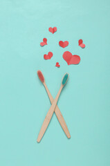 Eco bamboo toothbrushes and hearts on blue background. Romantic, love concept
