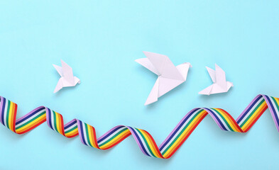Origami with pigeons and rainbow ribbon on blue background. Peace and love concept