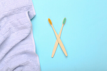Eco-friendly bamboo toothbrush with towel on blue background.