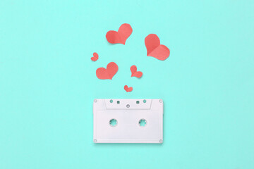 White painted audio cassette and hearts on blue background. Minimalism. Top view