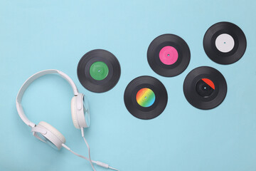 Musical layout. Headphones and vinyl records on a blue background. Top view. Flat lay