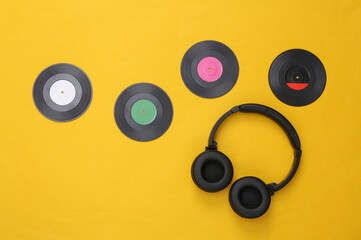 Musical layout. Headphones and vinyl records on yellow background. Top view. Flat lay