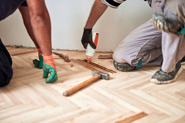 Repairman restoring parquet with a sanding machine.
