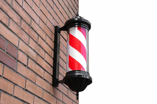 striped Barber shop pole on the brown brick wall. Barbershop pole against brick wall on the street