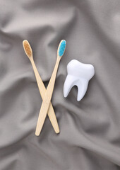 Eco bamboo toothbrushes and tooth on silk gray background