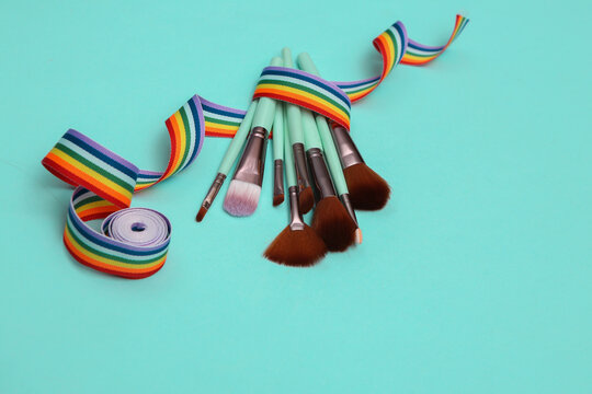 Makeup brushes with rainbow tape on blue background. Beauty layout.