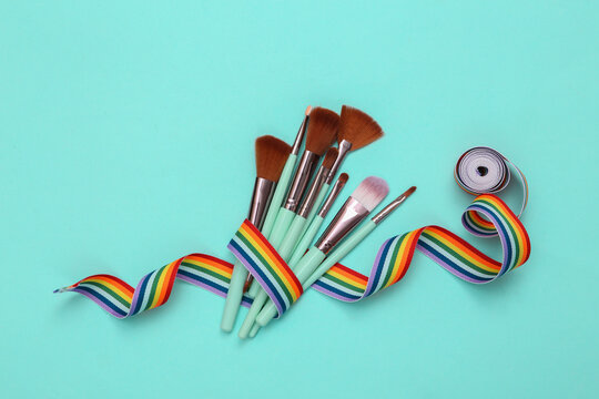 Makeup brushes with rainbow tape on blue background. Beauty layout.