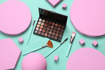 Make up eye shadow palette and brushes with different geometric shapes on blue background. Minimalism. Creative beauty layout