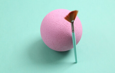Minimalistic beauty scene. Makeup brush with pink ball on blue background.